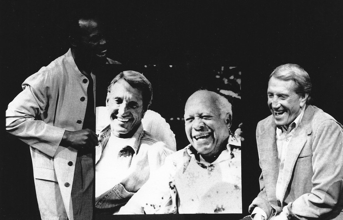 Three people laughing with a framed photo.