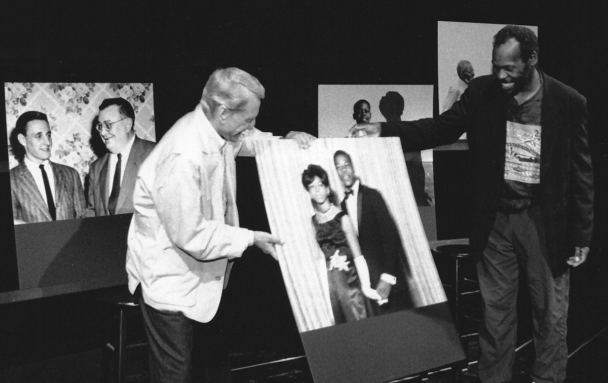 Two men holding a framed black-and-white photograph.