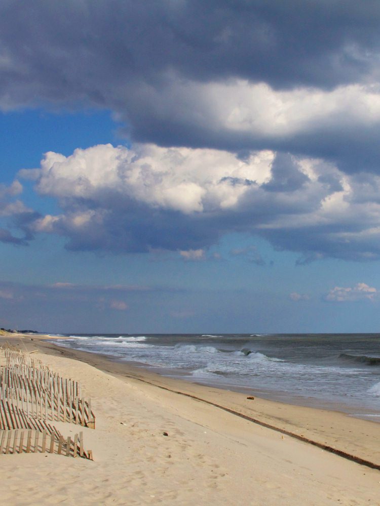 Sandy beach with clouds and ocean waves.
