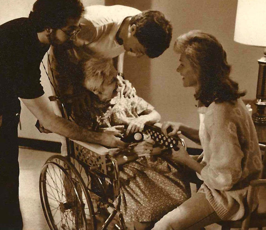 People assisting woman in a wheelchair.